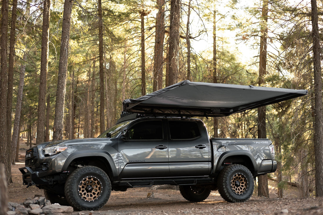 Taruca Rogue 8FT awning deployed on the side of a vehicle in a forest camp