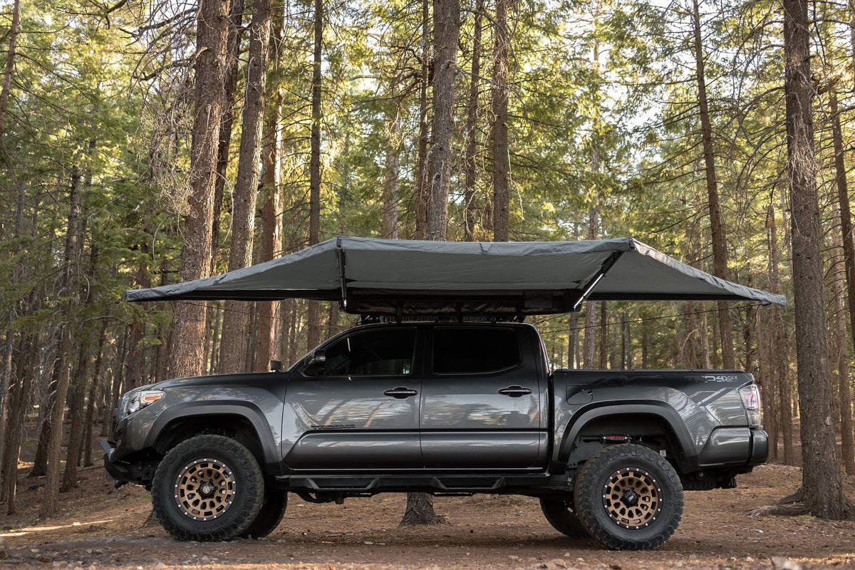 Taruca Rogue 180 awning Tacoma with large grey wing awning deployed in forest