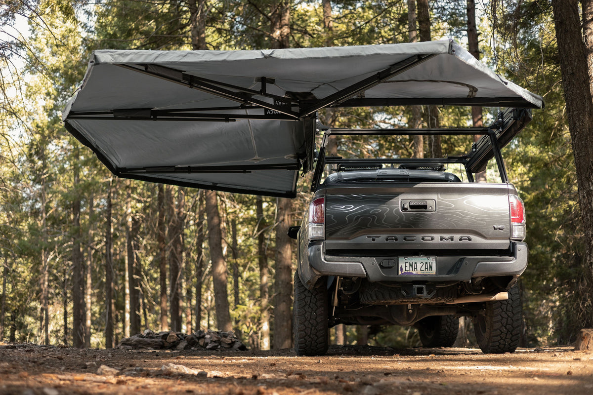 Taruca 270+ XC awning deployed over Tacoma rear and side from behind in woods
