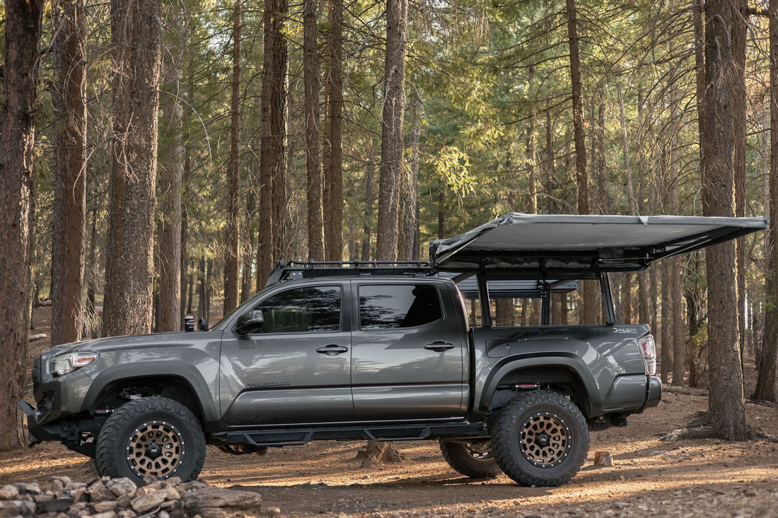 Taruca Rogue 6FT awning deployed on the side of a vehicle in a forest camp