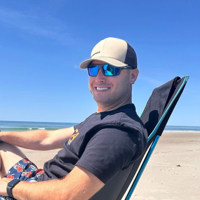 Man sitting on a beach chair at the beach with a clear blue sky.