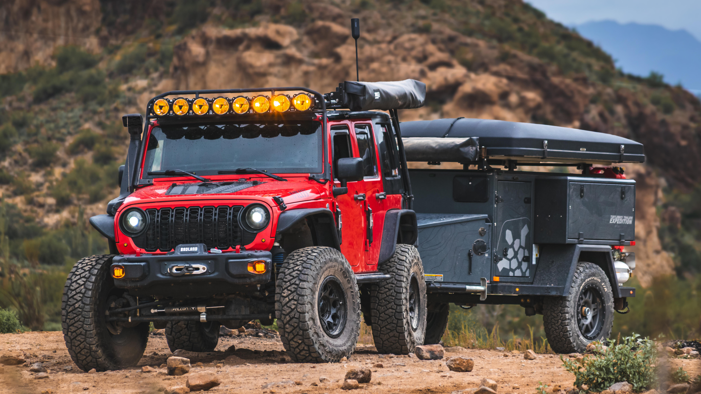 Red off-road vehicle with a camper shell in a desert landscape