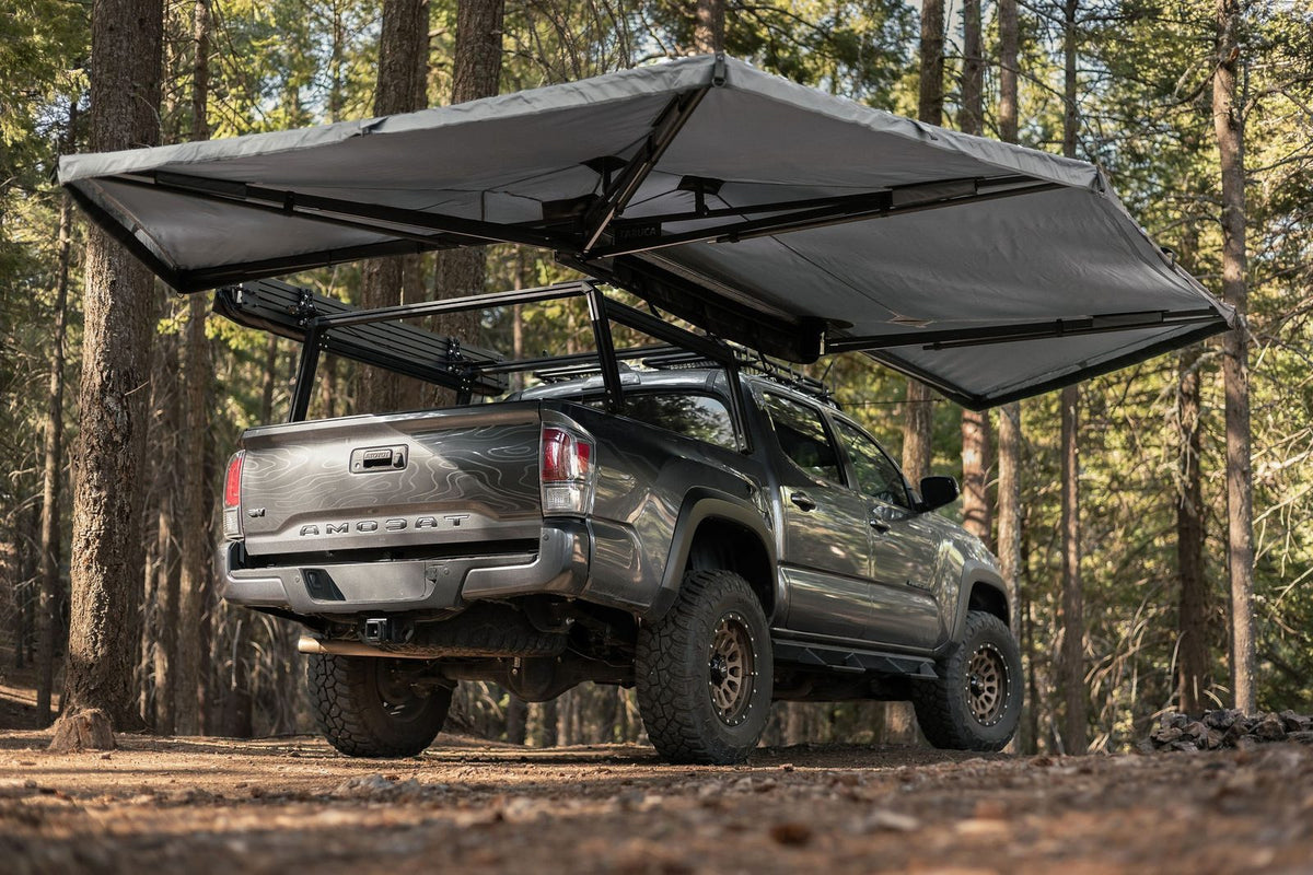 Taruca Rogue 270+ XC awning deployed on a Toyota Tacoma in a pine forest, rear three-quarter view